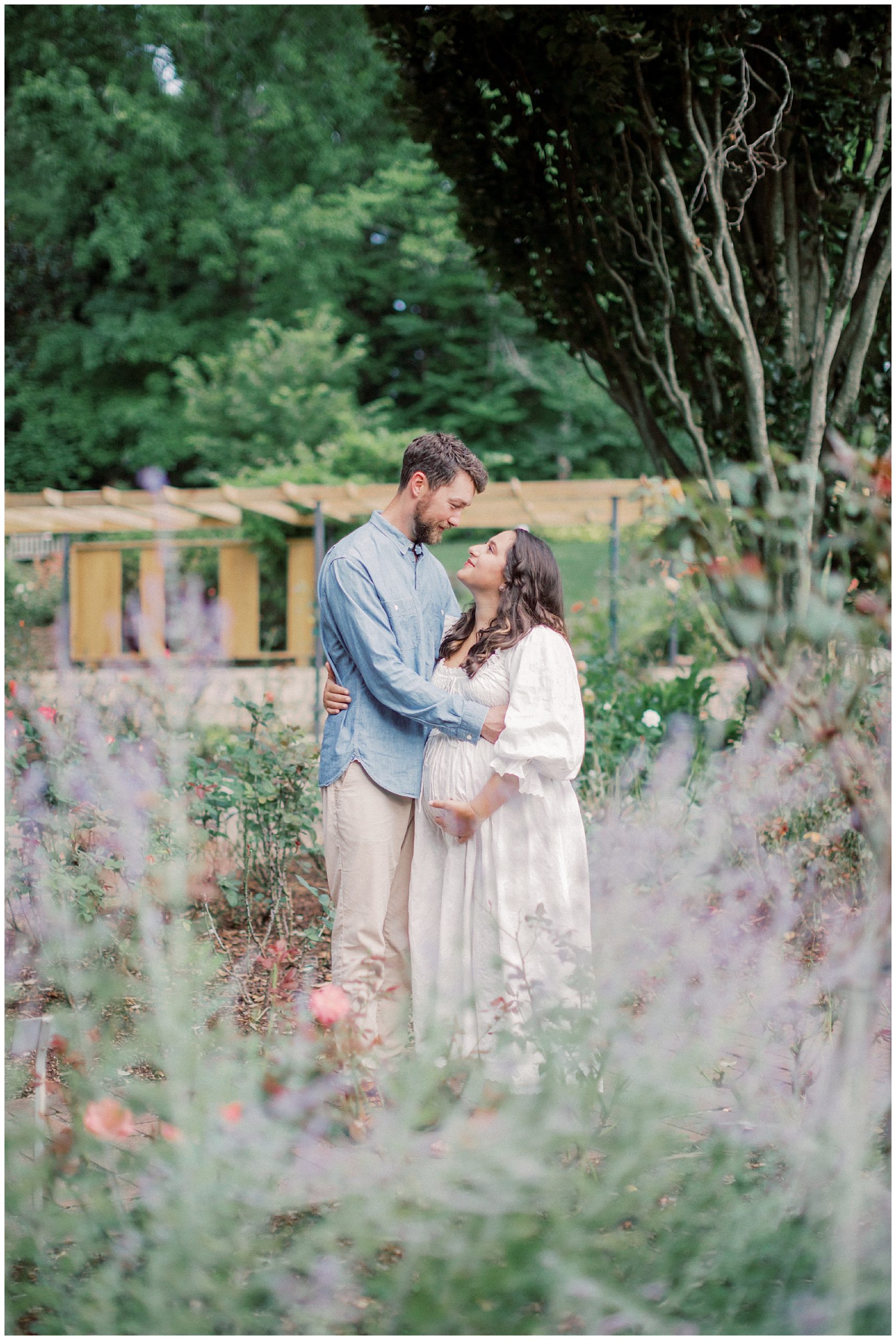 Expecting Couple Stand Together, Looking At One Another During Their Maternity Session At Brookside Gardens.