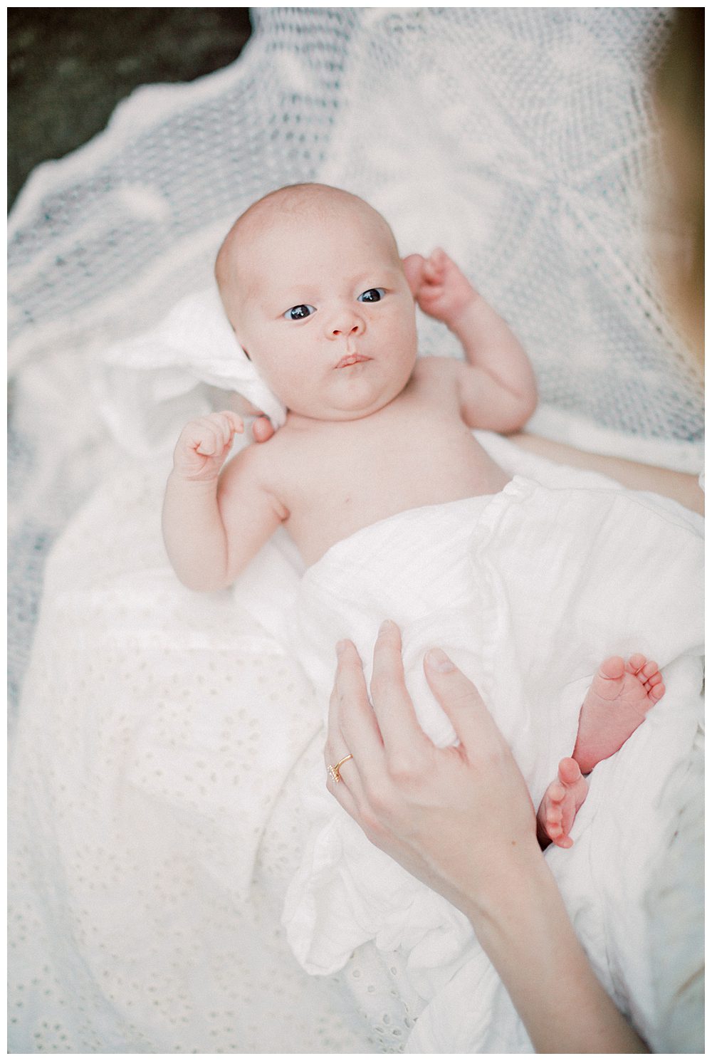 Newborn Baby Girl Looks At Camera While Being Held By Mother During Alexandria Va Newborn Session.