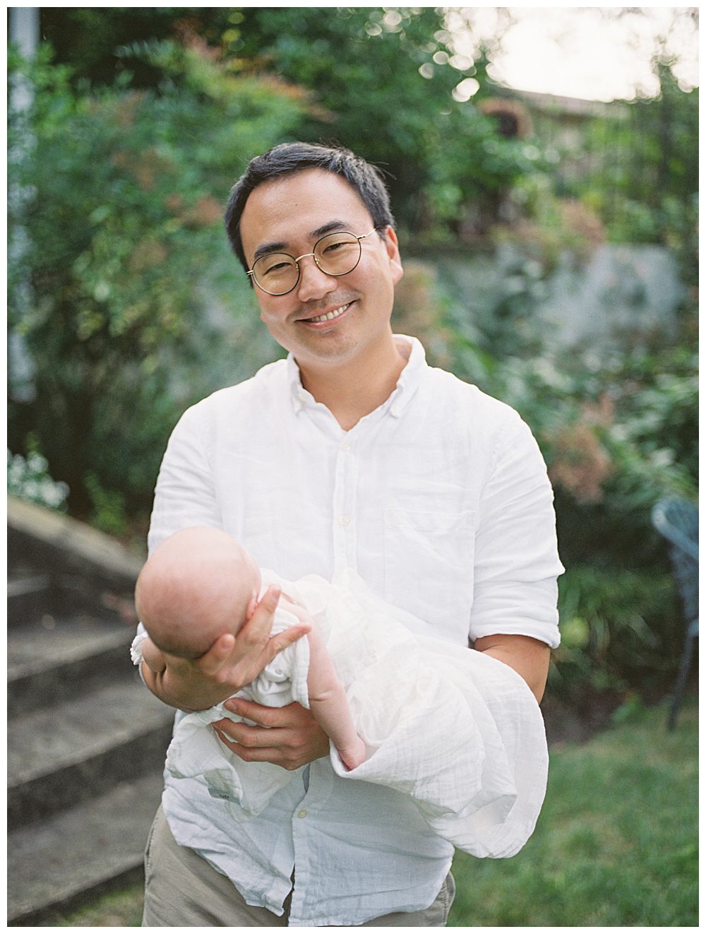 Father Holds Newborn Baby And Smiles At Camera.