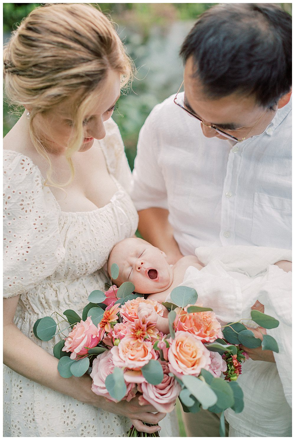 Newborn Baby Yawns While Sleeping In Parents Arms On Bouquet Of Roses.