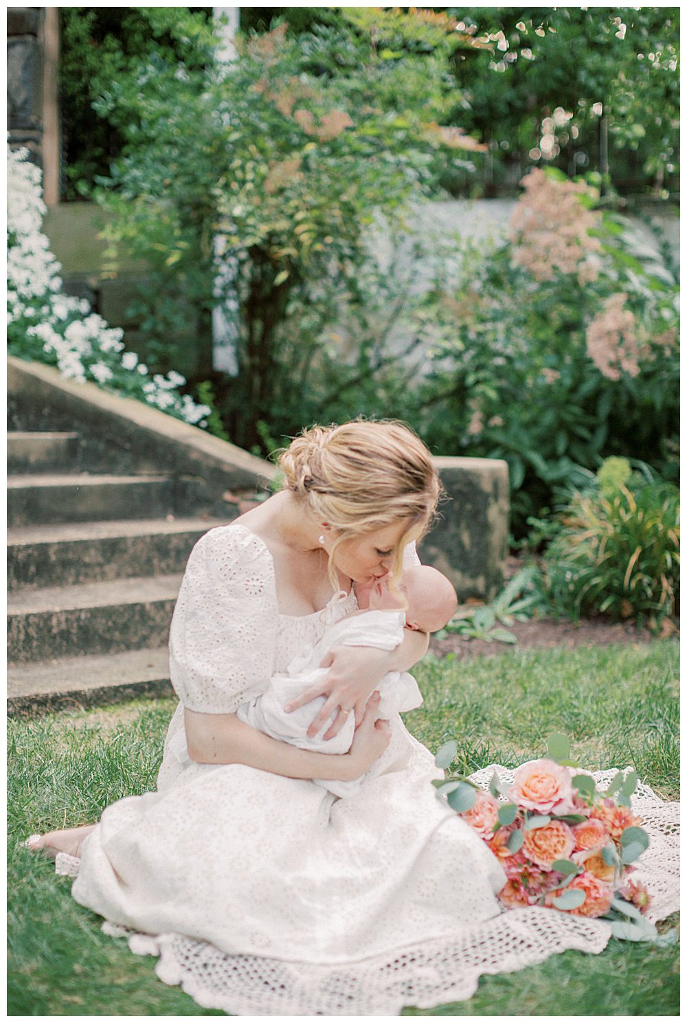 Blonde New Mother Holds Newborn Daughter While Sitting On Crochet Blanket During Outdoor Alexandria Va Newborn Session.