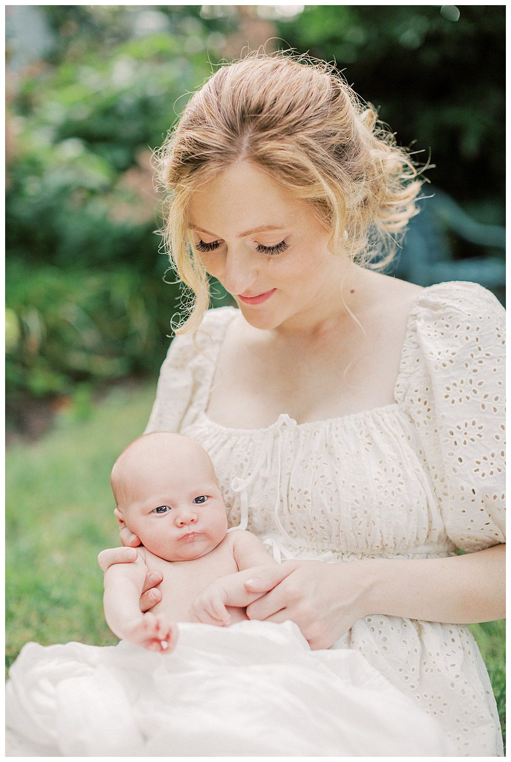 Mother Holds Up Newborn Baby On Her Lap.