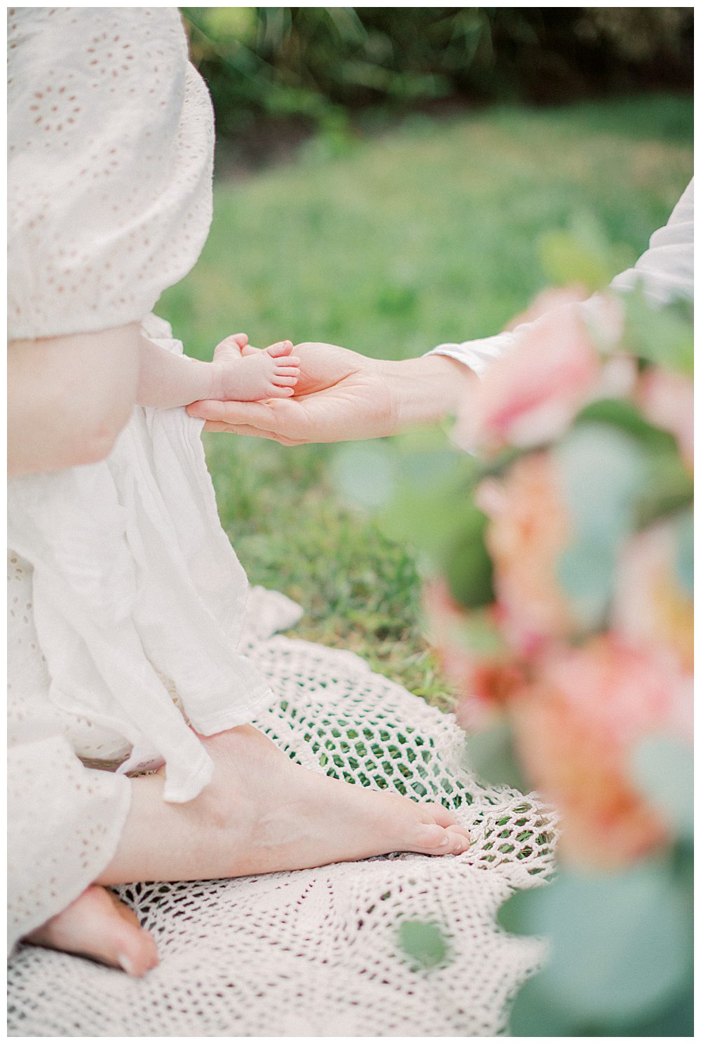 Newborn Feet Held In Hands Of Father During Outdoor Newborn Session.