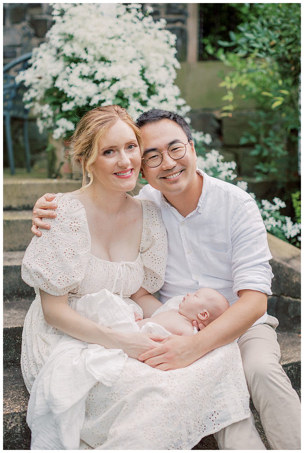 Mother And Father Hold Their Newborn Daughter And Smile At The Camera During Alexandria Va Newborn Session.