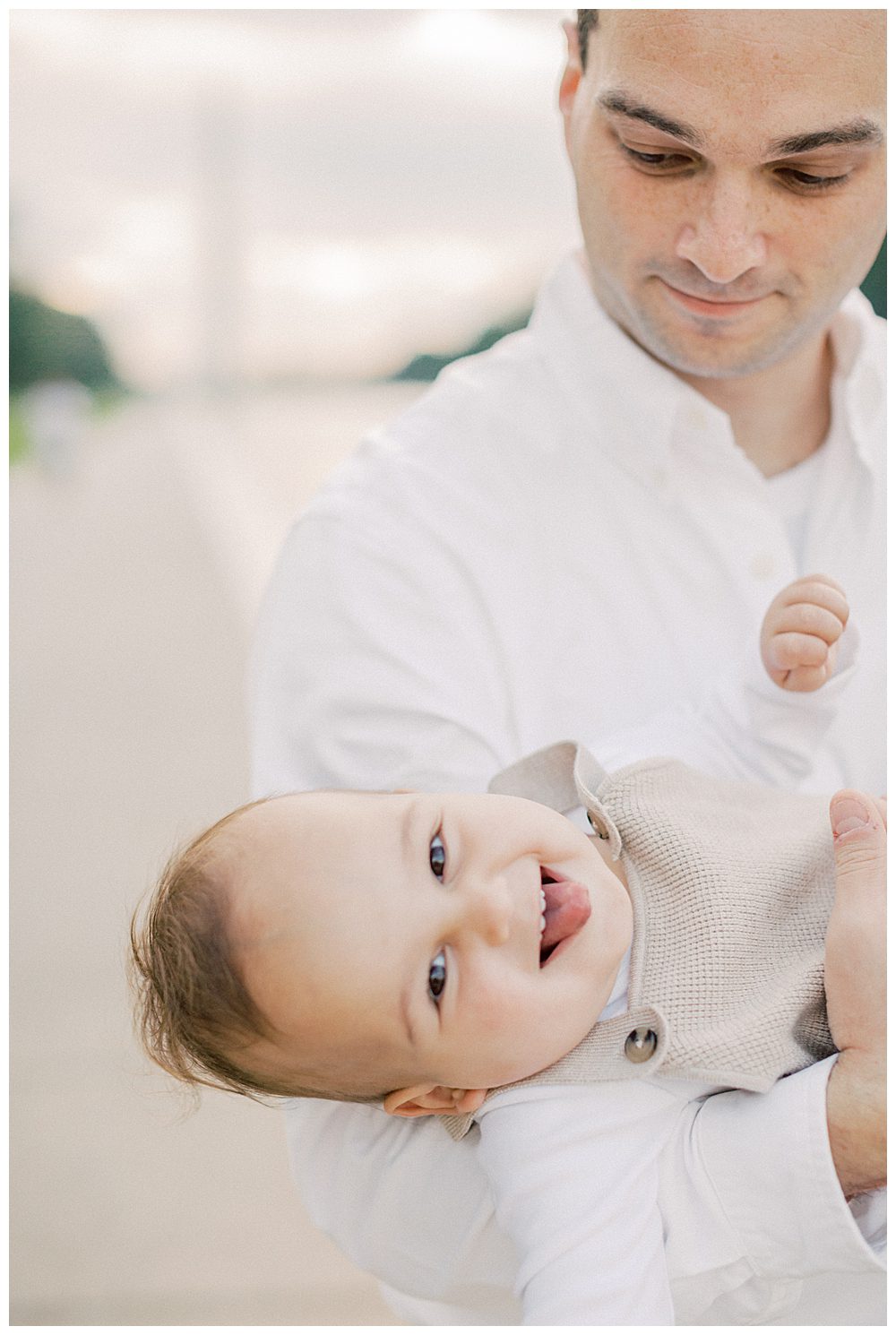 Toddler Boy Smiles While Dad Holds Him Sideways.