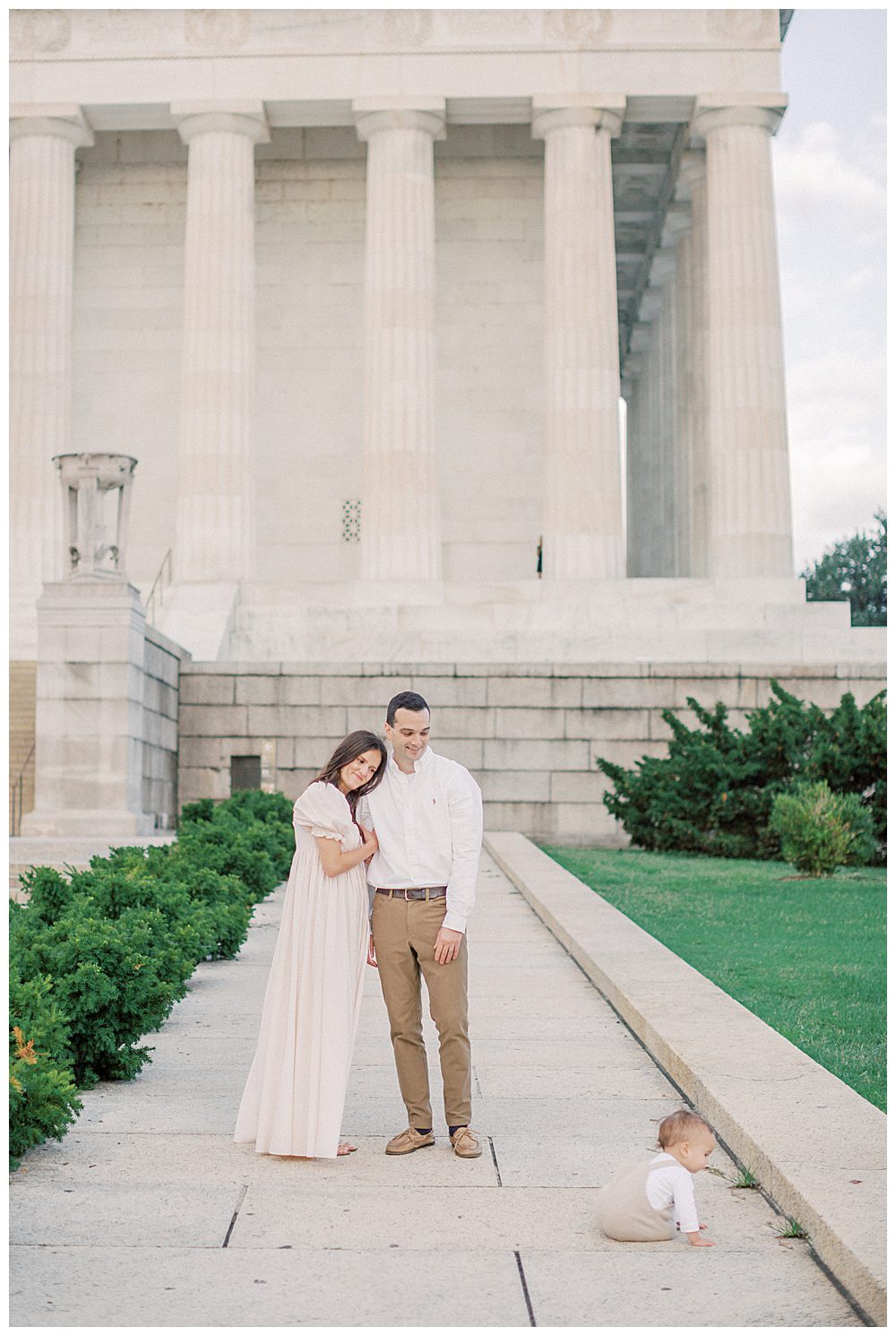 Mother Leans On Father's Shoulders While They Watch Their Son Crawl In Front Of The Lincoln Memorial.