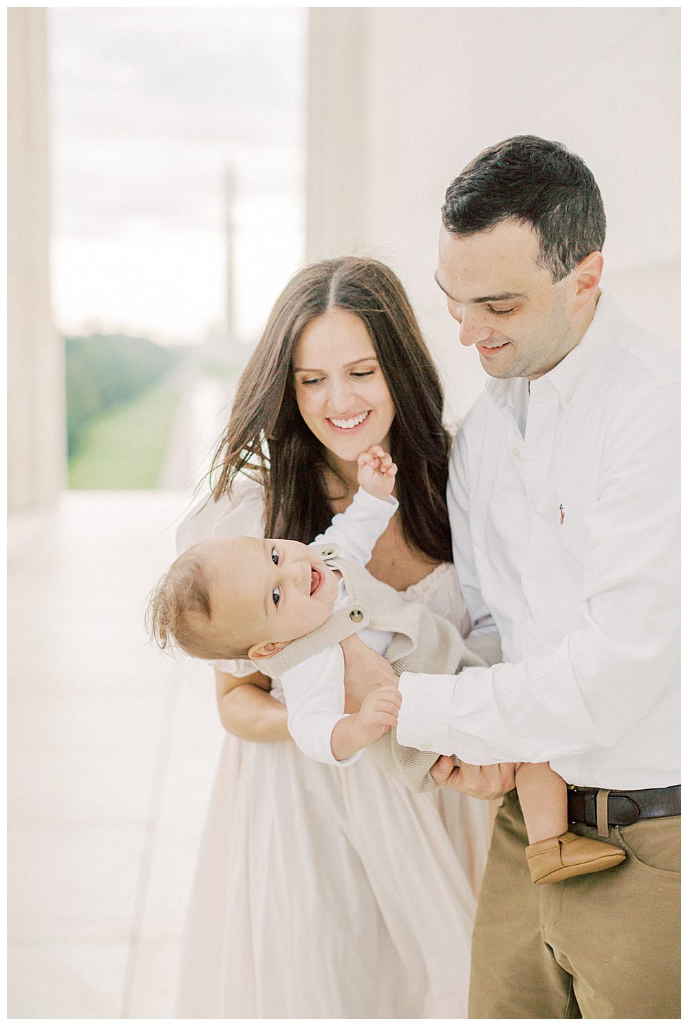 Toddler Boy Smiles While Parents Hold Him In The Lincoln Memorial.