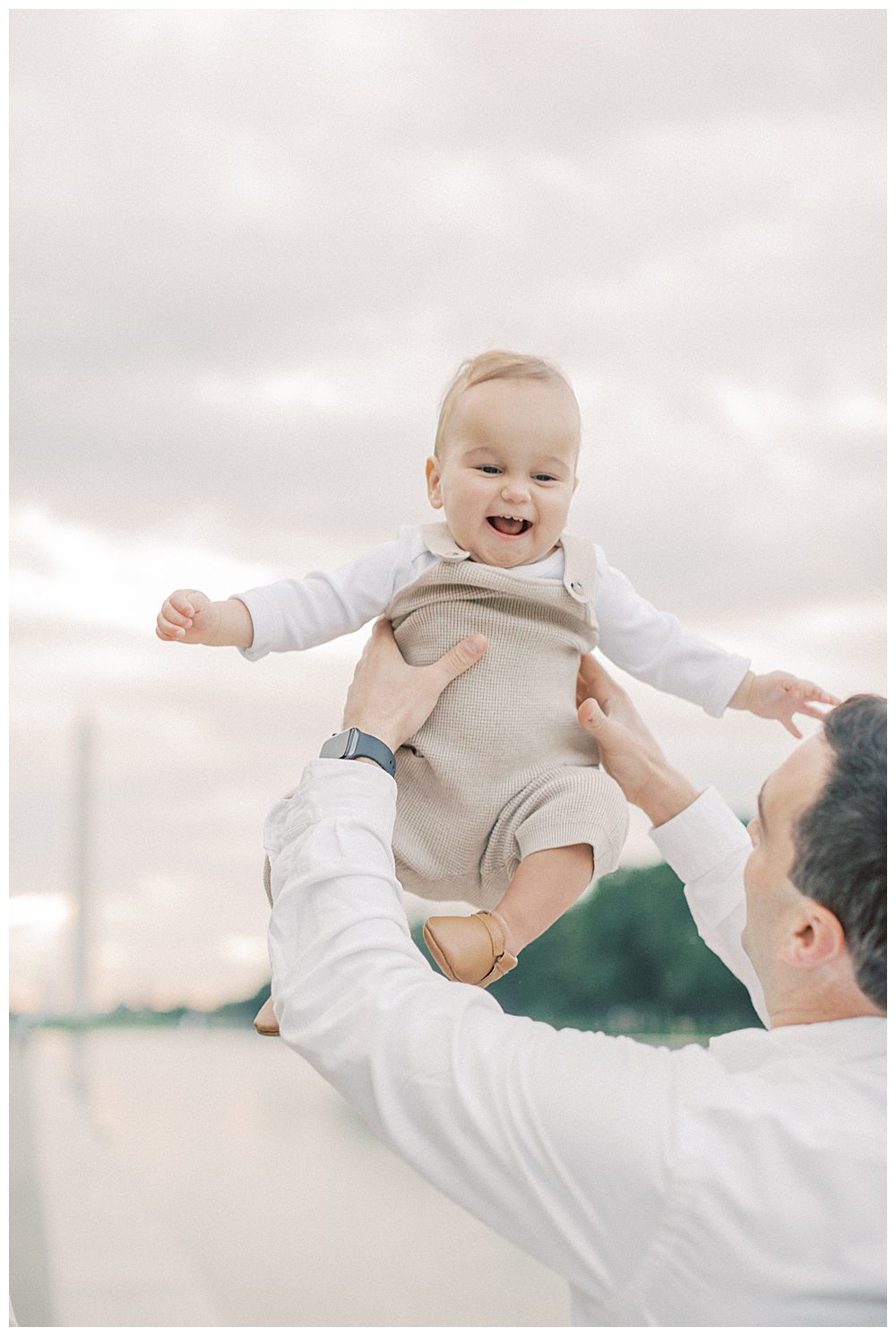 Little Boy Is Held Up In The Air In Front Of The Washington Monument.