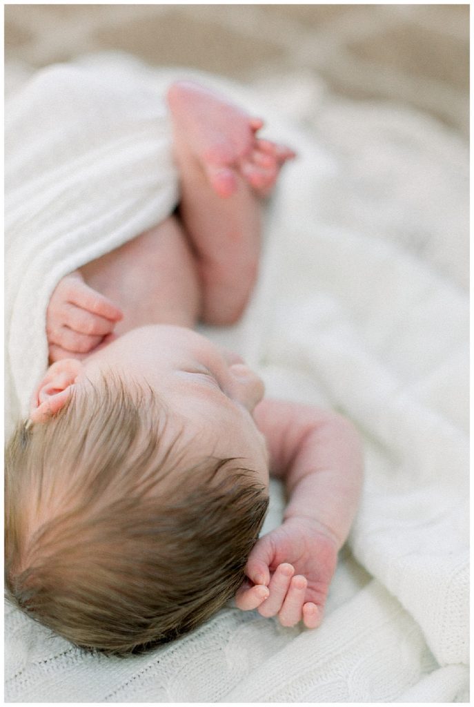 Baby With Brown Hair Lays On Knit Blanket During Great Falls Newborn Session.