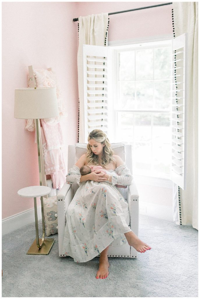 Blonde Mother Nurses Her Newborn Girl While Wearing The Doen Bijou Painted Floral Dress.