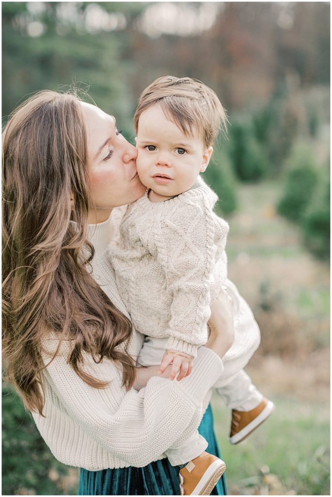 Mother Kisses Her Son's Cheek At Christmas Tree Farm