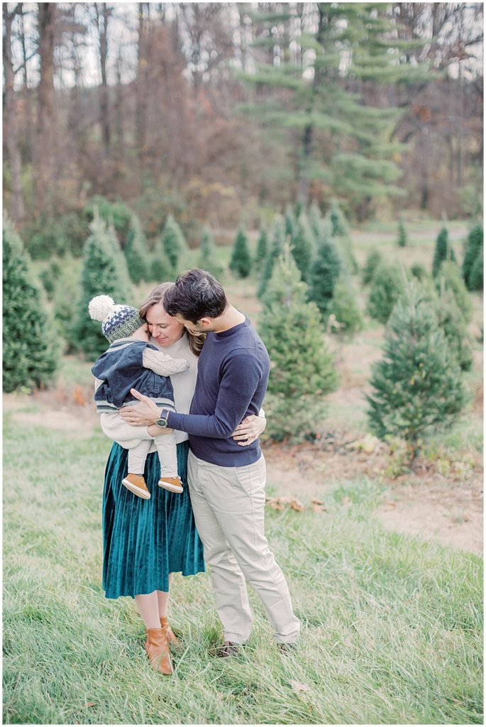 Parents Hug Their Infant Son During Christmas Mini Sessions At Butler's Orchard.