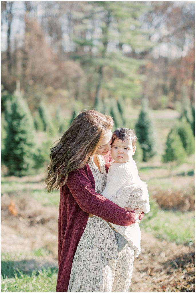 Mother Leans Into Her Infant Son During Christmas Mini Sessions At Butler's Orchard.