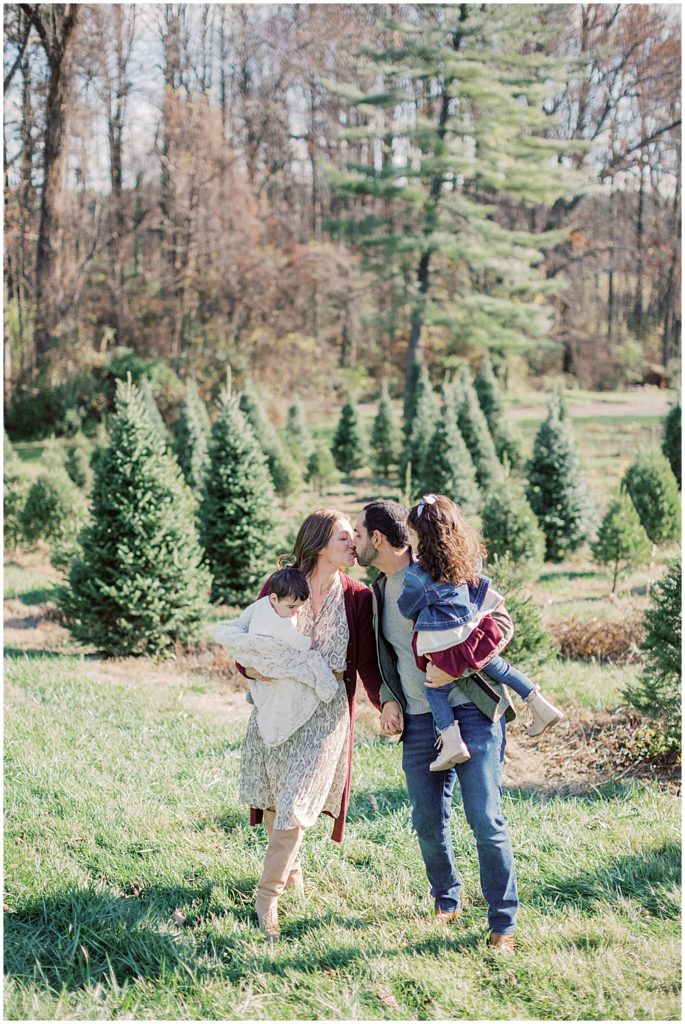 Two Parents Kiss During Christmas Mini Sessions At Butler's Orchard