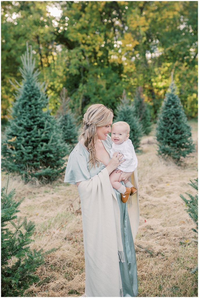 Mom Snuggles Baby During Christmas Tree Farm Mini Sessions At Butler's Orchard.