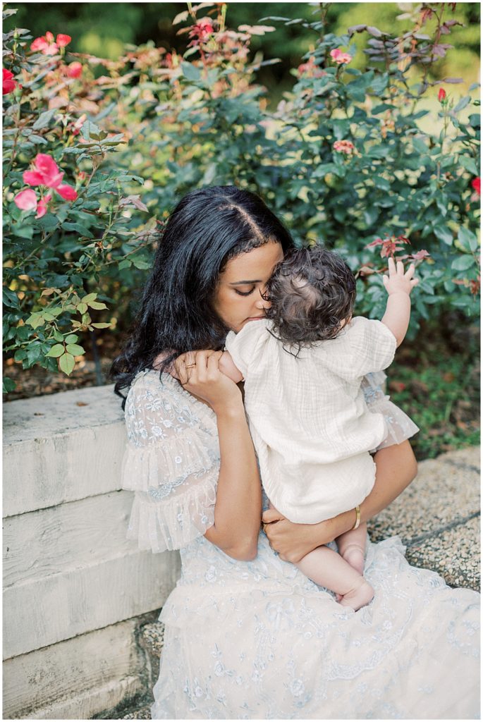 Mother In Blue Needle &Amp; Thread Dress Holds Infant Daughter Close To Her During Montgomery County Family Session At Brookside Gardens.