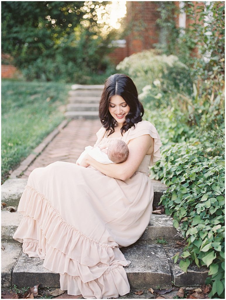 Mom Sits On Brick Steps In Gardens At Oatlands Historic Home During Newborn Session By Loudoun County Newborn Photographer Marie Elizabeth Photography.