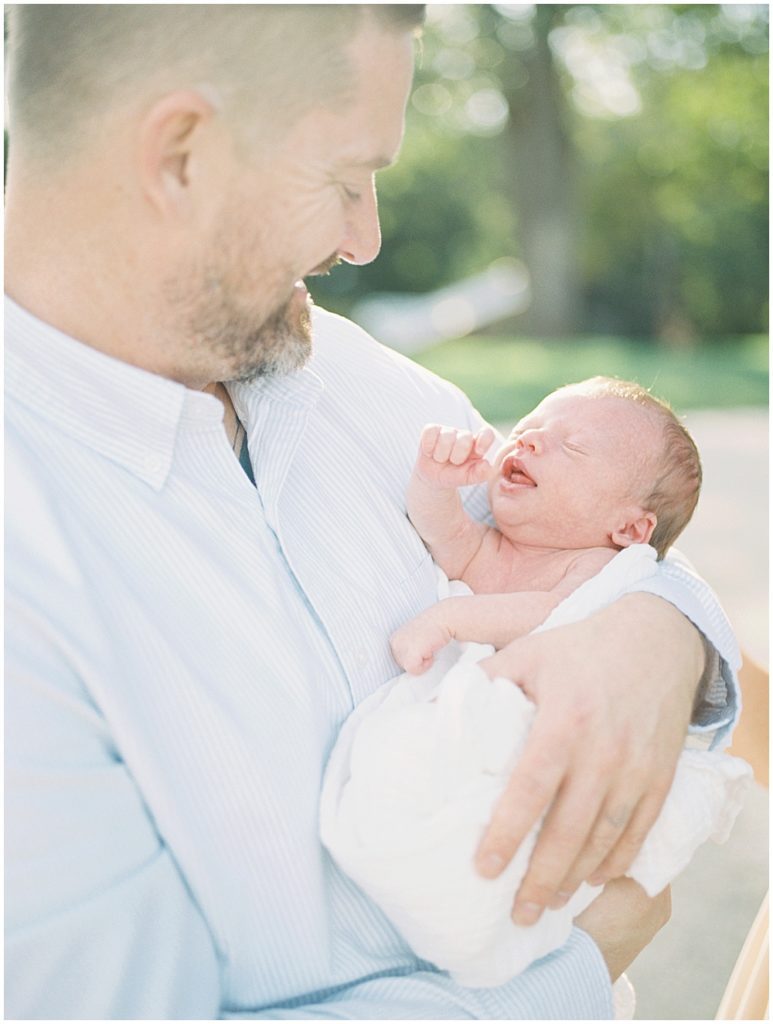 Father Smiles As He Holds His Newborn Son.