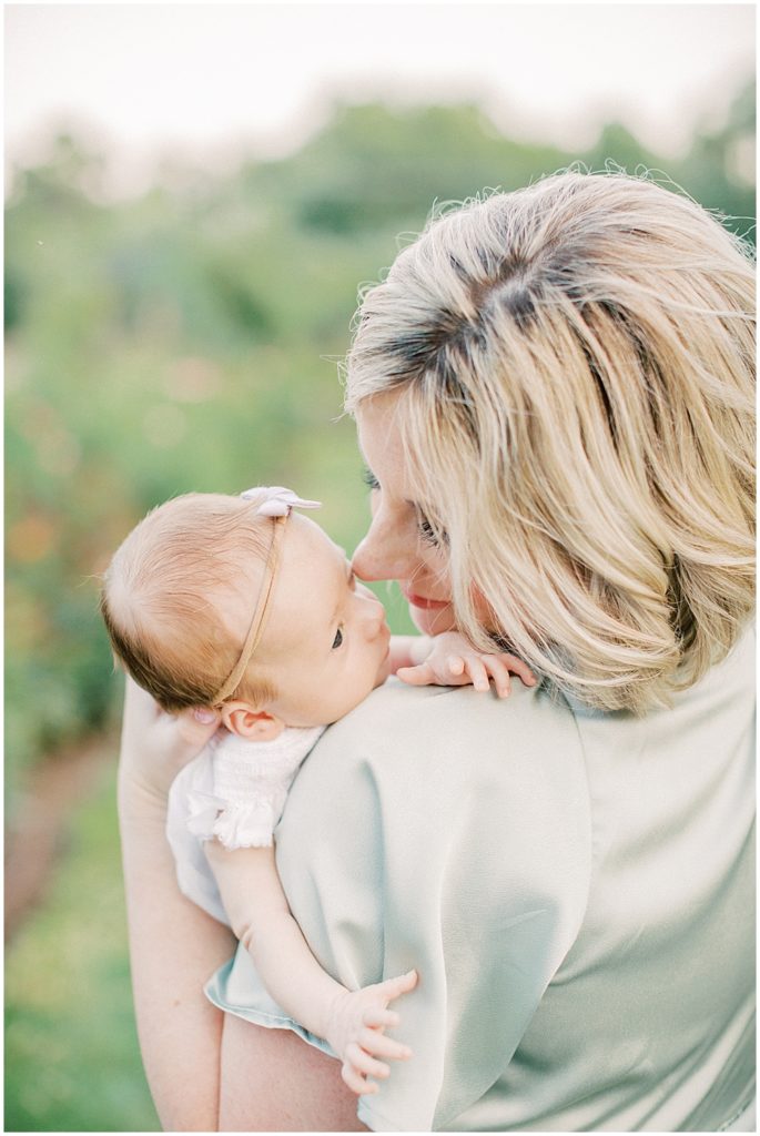 Mother Leans In To Nuzzle Her Newborn Baby Girl During Outdoor Newborn Session.