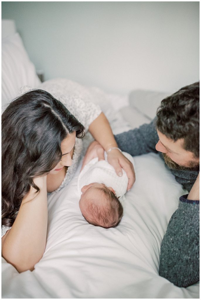 Mother And Father Lay On Bed With Baby Boy During Dc Row House Newborn Session.