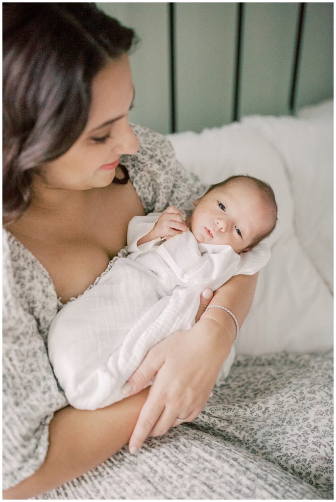 Baby Boy Looks At Camera As He Is Held By His Mother During Dc Row House Newborn Session.