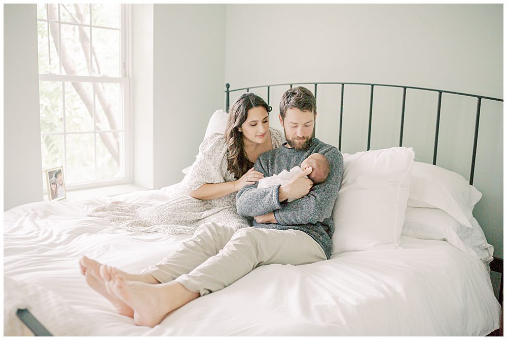 Parents Sit On Bed Holding Newborn Baby During Dc Row House Newborn Session.