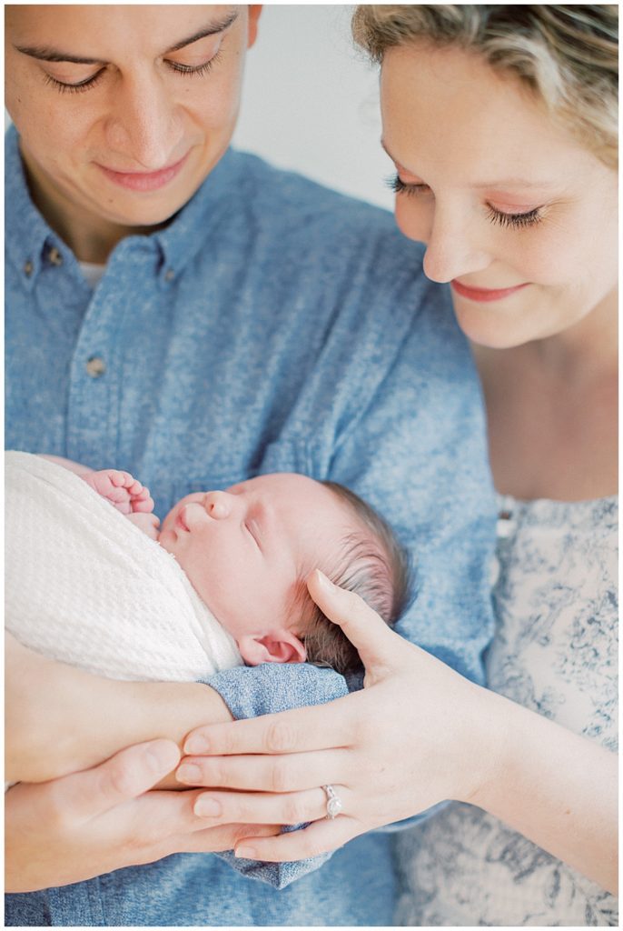 Mother Caresses Daughter While Husband Holds Her During Fairfax Va Newborn Session.