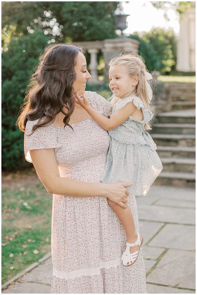 Little Girl Held By Her Mother Traces Her Mother's Face During Glenview Mansion Photos By Marie Elizabeth Photography.