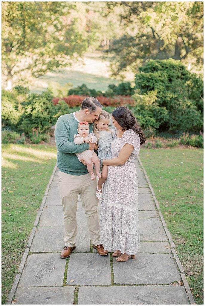 Parents Hold Their Two Young Daughters On Stone Pathway During Glenview Mansion Photos By Marie Elizabeth Photography.