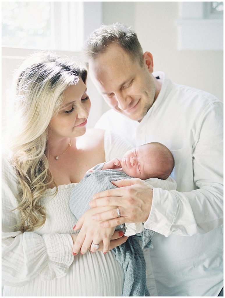 Mother And Father Hold Their Newborn Baby And Smile During Newborn Session With Dogs In Washington, Dc.