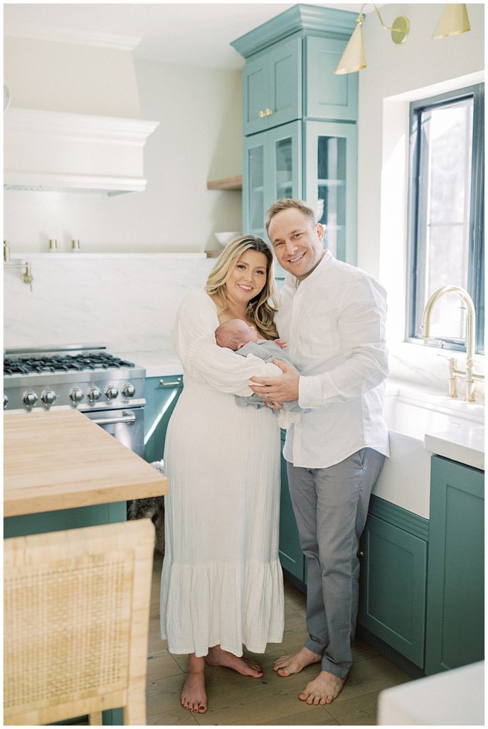 Mother And Father Hold Their Newborn Baby While Standing In Their Kitchen In Washington, Dc.