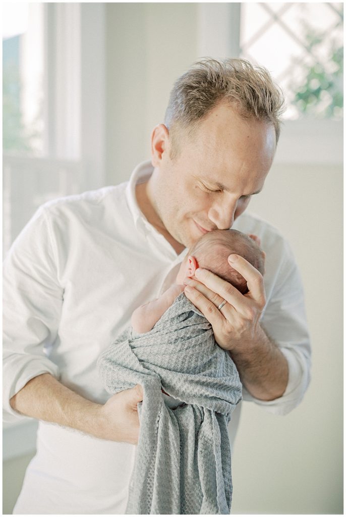 Father Brings His Newborn Baby Up For A Kiss During Washington Dc Newborn Session.