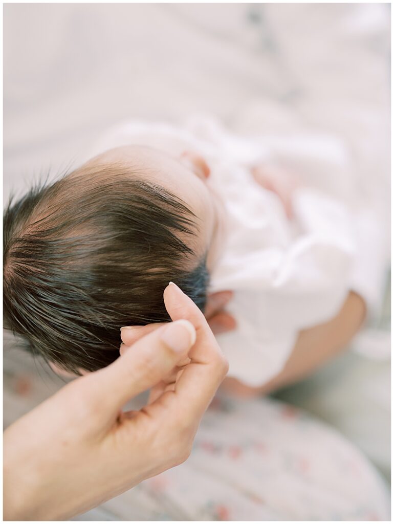 A Baby Is Held By Her Father As Her Other Takes Her Fingers To Stroke Her Hair Photographed By Arlington Newborn Photographer Marie Elizabeth Photography.