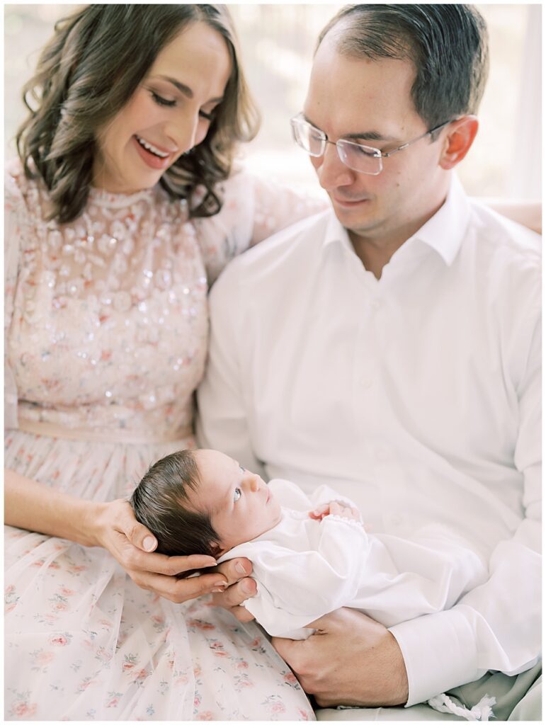 Mother And Father Gaze Down At Their Baby Girl During Their Northern Virginia Newborn Session.