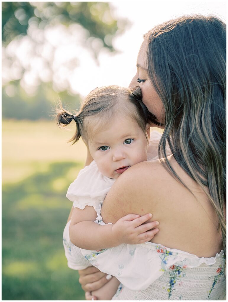 Mother Leans Into Toddler Daughter As She Looks At The Camera During Manassas Battlefield Family Session.