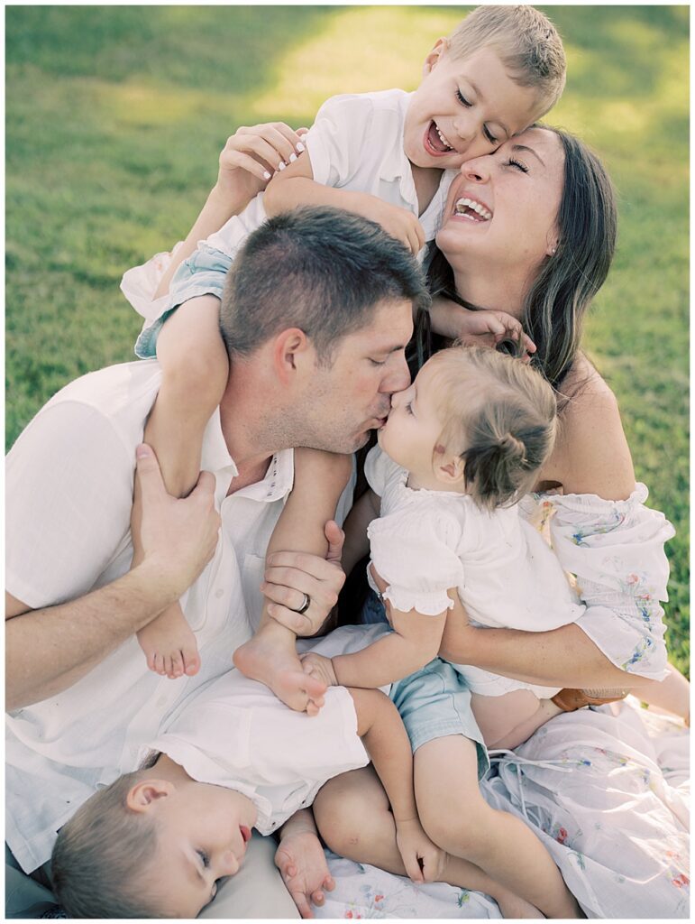 Family Of Five Sit Together On Blanket Leaning Together For A Hug During Manassas Battlefield Family Session.