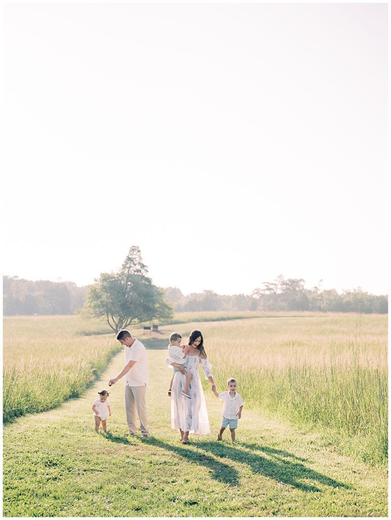 Mother And Father Walk With Three Young Children Through An Open Field During Manassas Battlefield Family Session.