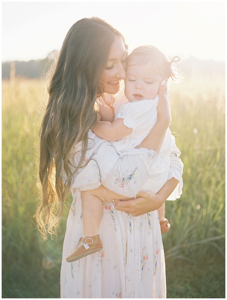 Mother With Long Brown Hair Holds Her Toddler Daughter Up To Her.