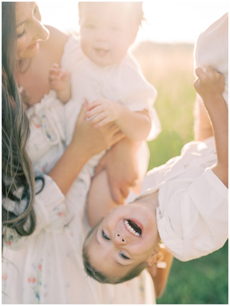 Little Boy Thrown Back Laughing During Manassas Battlefield Family Session At Sunrise.