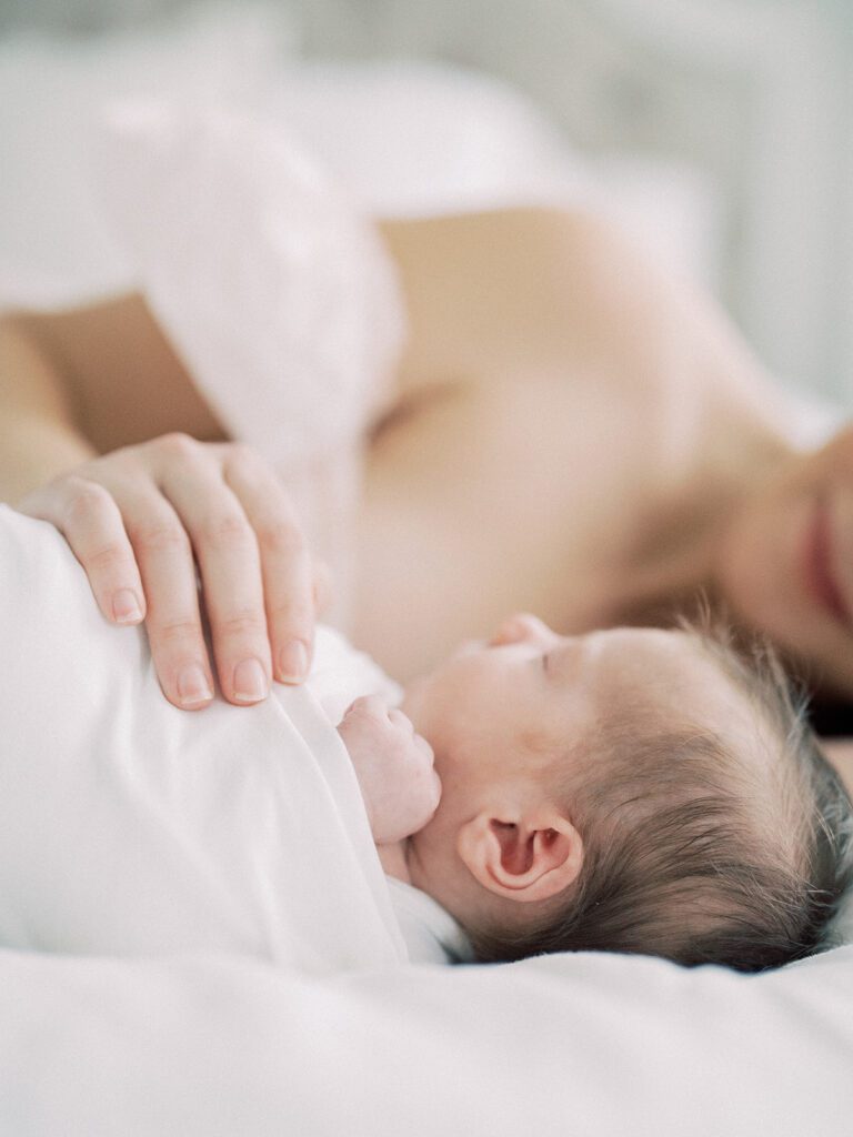 Close-Up Of Hand On Swaddled Baby.