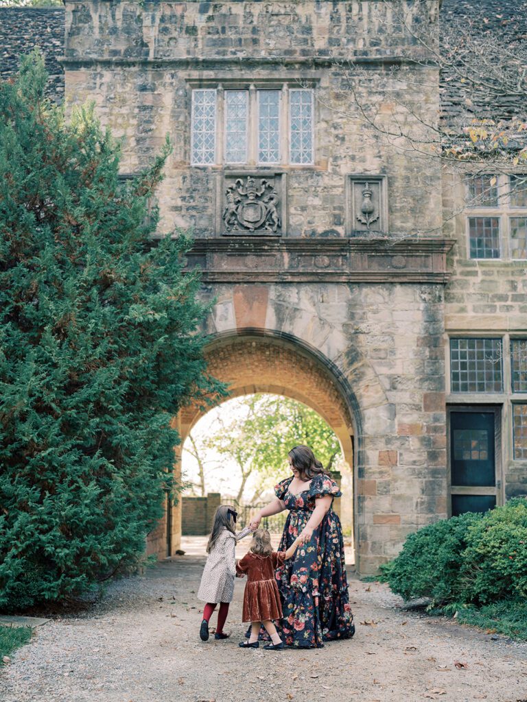 A mother in a black Selkie floral dress dances with her two young daughters during a Virginia House family session in Richmond, VA.