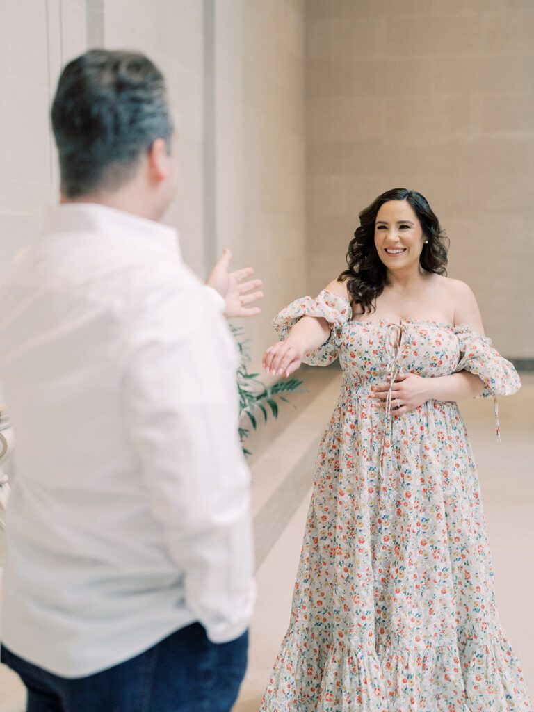 Pregnant Mother In Floral Doen Dress Walks With Hand Stretched Out To Her Husband During Their National Gallery Of Art Maternity Session.