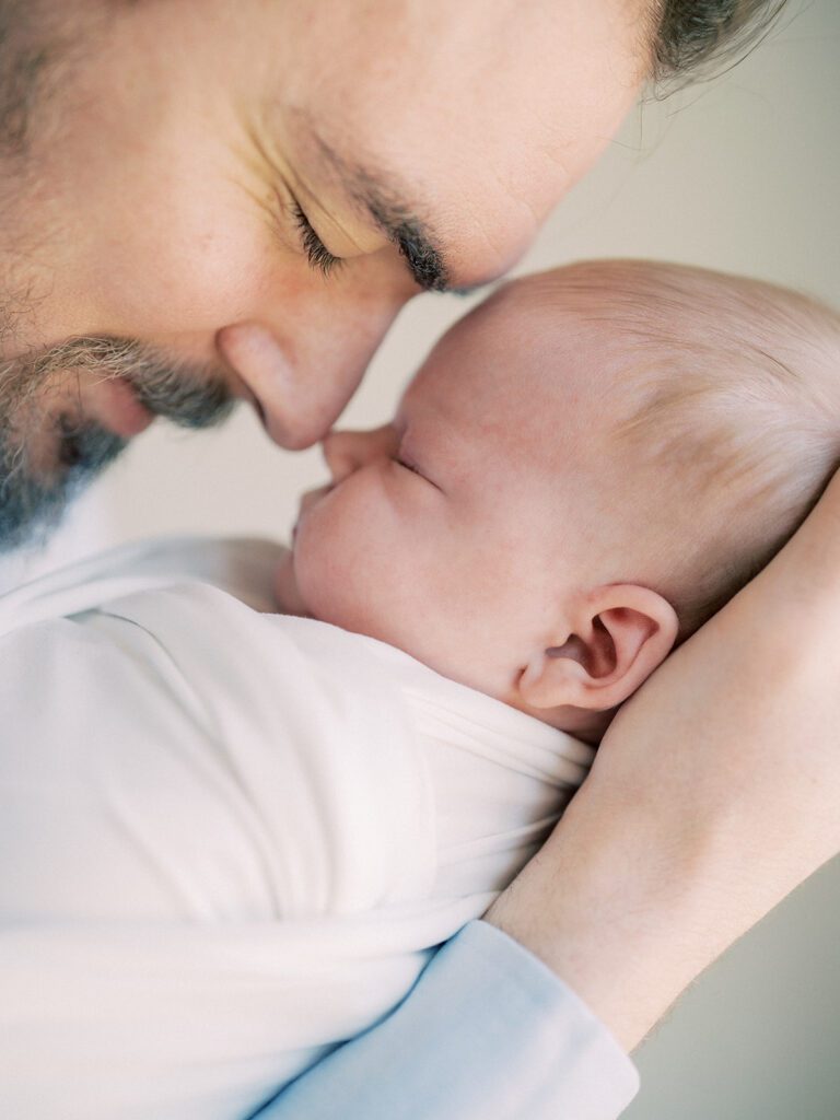 Close-Up View Of Father Going Nose-To-Nose With Newborn Baby.