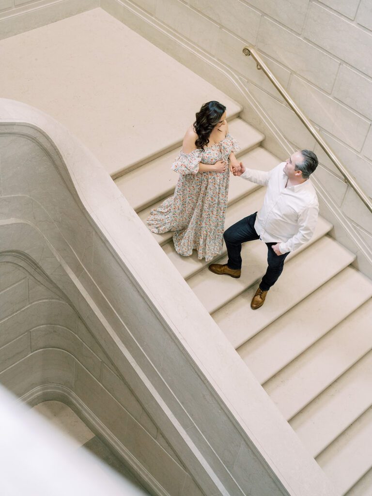 Expecting Couple Walk Down Stairs During Their National Gallery Of Art Maternity Session.