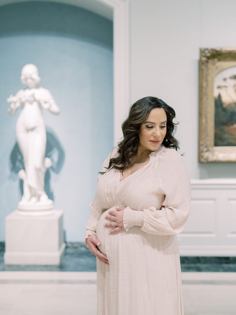 Mother With Brown Hair Stands With Hands On Her Belly During Her National Gallery Of Art Maternity Session.