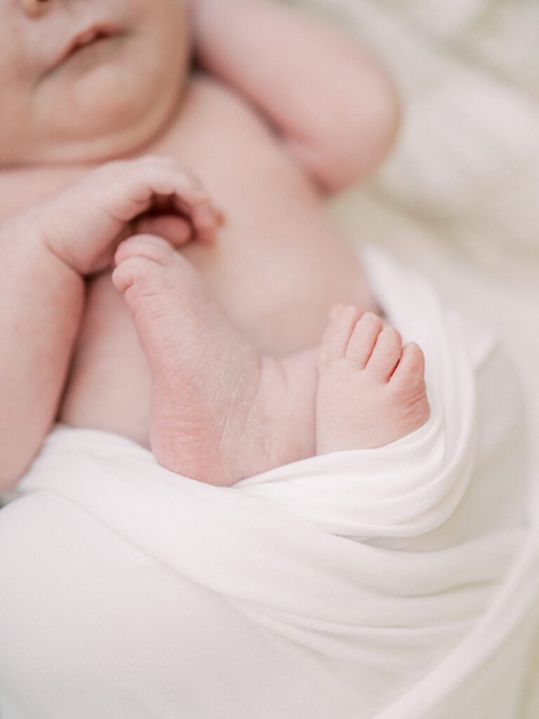 Close-Up View Of Baby Feet Swaddled In White.