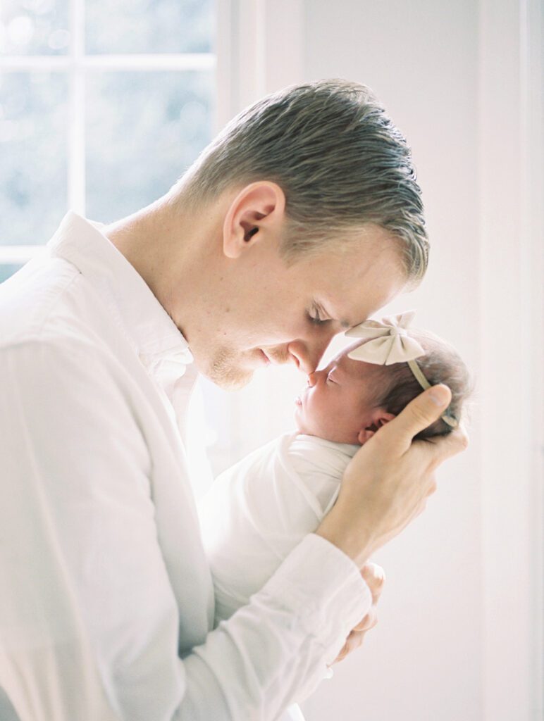 A Father Brings His Newborn Baby Girl Up Nose-To-Nose.