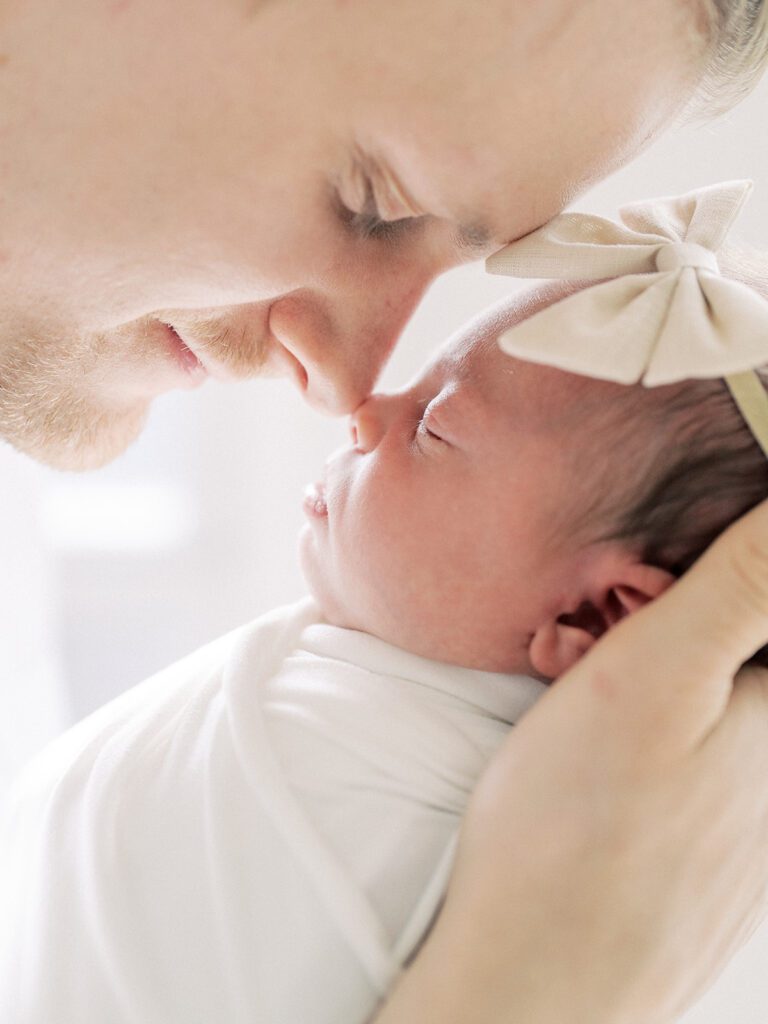 A Close-Up View Of A Father Going Nose-To-Nose With His Newborn Baby Girl.