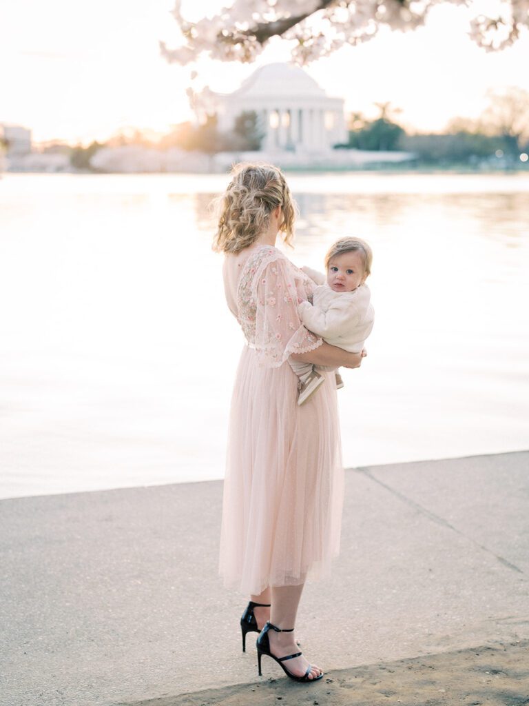 Blonde Mother Stands Along The Tidal Basin Holding Her Young Son.