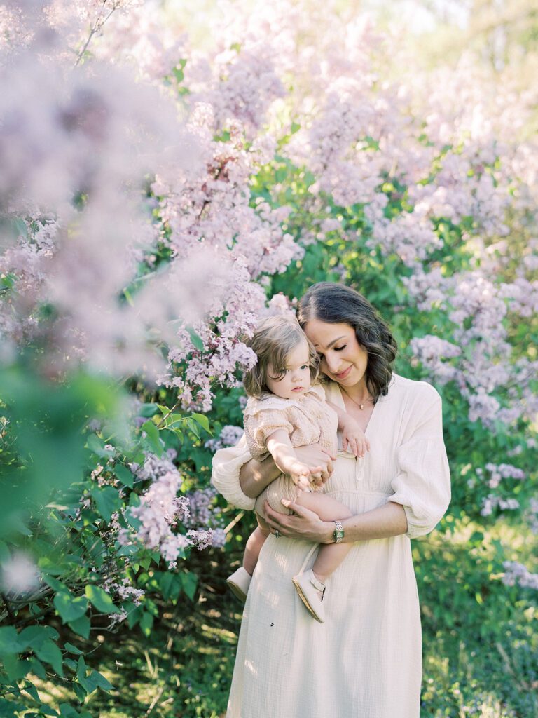 Mother with brown hair and ivory dress holds her toddler daughter in a lilac field at the National Arboretum, photographed by Bethesda Photographer Marie Elizabeth Photography.